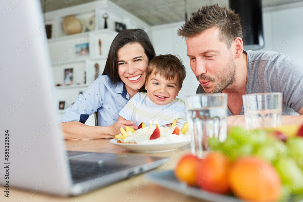 Family blows out candles on the cake in video chat