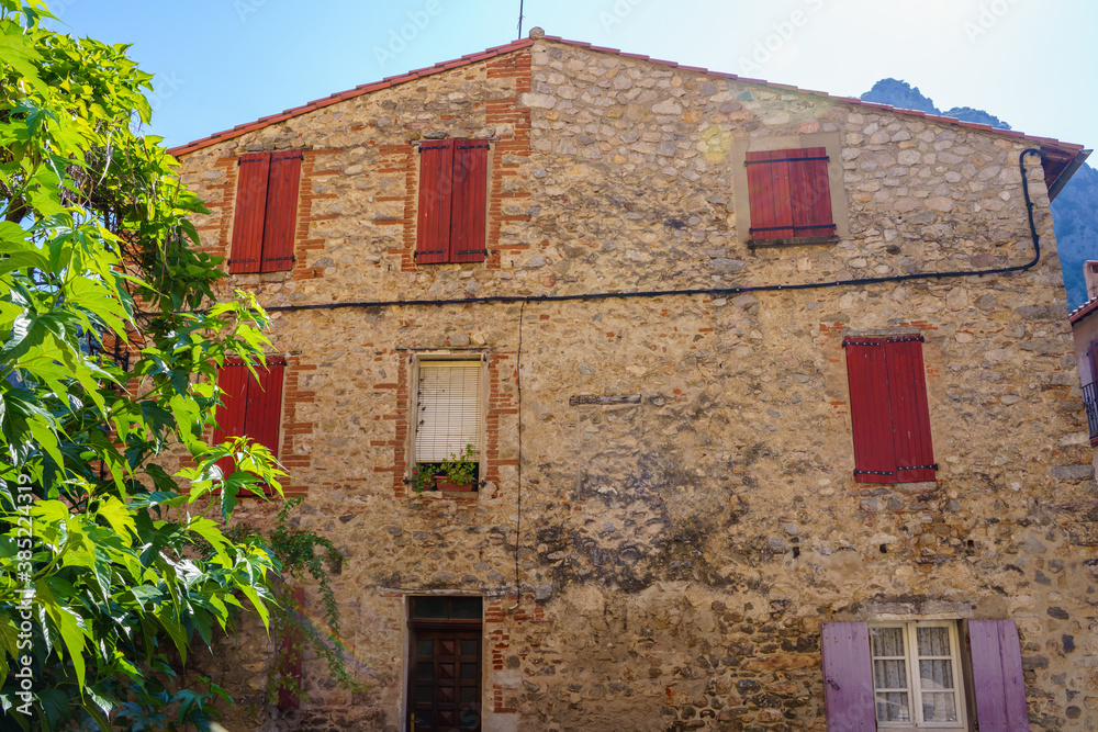 Facade of a rural stone house with colored window frames