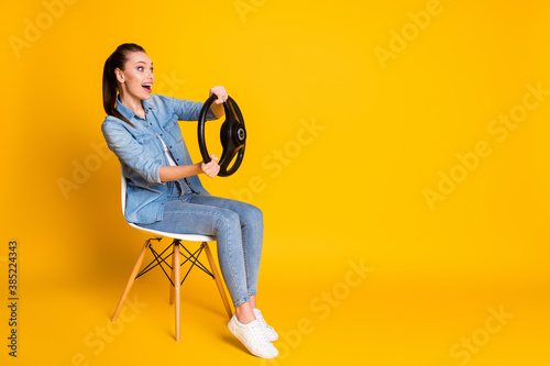 Full size profile side photo surprised girl travel drive car hold steering wheel sit chair look copyspace wear style trendy jeans clothes isolated bright shine color background