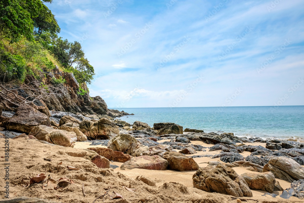 Beautiful rocky beach. Coast with tropical greenery. Turquoise sea and blue sky with clouds
