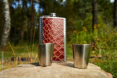 Metal flask with measuring cups. A flask for alcohol.