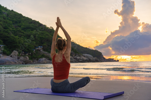 Obraz na płótnie Woman practices yoga. Adult woman raising hands while meditating against colorful morning sky w salonie