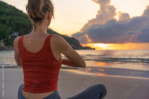 Obraz na płótnie Woman practices yoga. Woman sitting in lotus position and meditating at sunrise on the beach w salonie