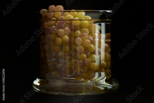 Bunches of grapes in an aquarium with water, on a black background.
