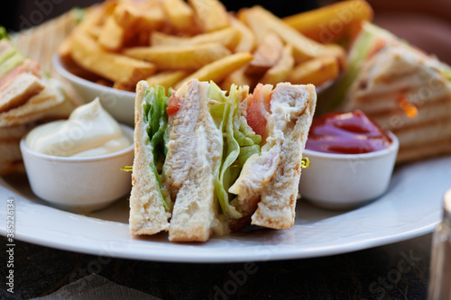 klassischer Clubsandwich Toast mit Huhn Pute Salat und als Beilage Pommes mit Ketchup und Mayonnaise  photo