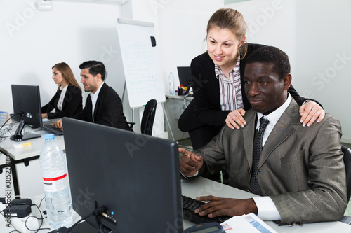 Flirting between coworkers in office during working at laptop photo