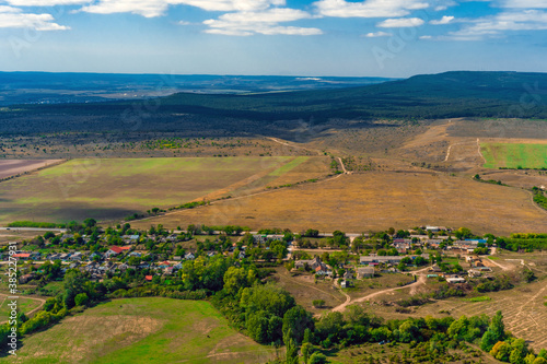 Top view of the dirt road with a crossroads and dense green forests and fields. Beautiful bright landscape photography on a summer day