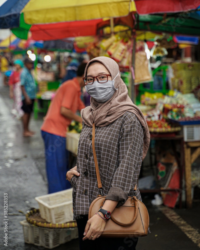 Muslim women wearing health cloth masks while in traditional markets shopping for vegetables.