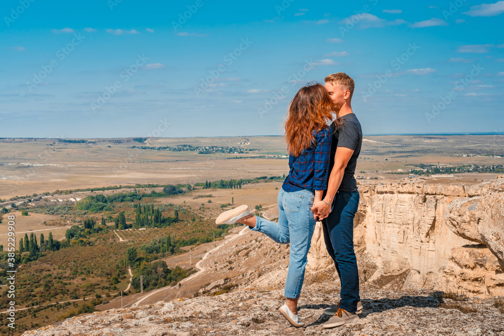 A romantic couple a man and a woman stand on the edge of a cliff on a White rock in the Crimea with a view of the rural landscape A romantic couple a man and a woman stand on the edge of a cliff on a White rock in the Crimea with a view of the rural landscape