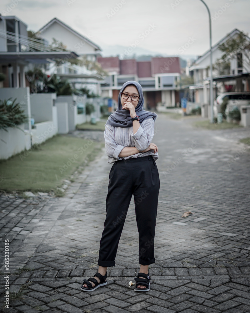 Beautiful Asian Muslim woman is standing posing and stylish in the middle of a luxury residential street.