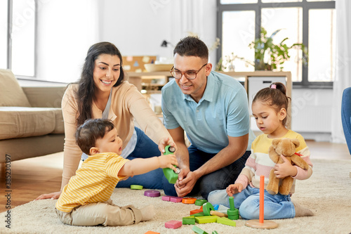 family and people concept - happy mother, father, little daughter and baby son playing with wooden toys at home