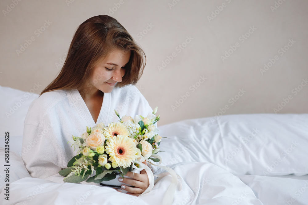 A woman in bed with a bouquet of flowers. A woman in bed with a bouquet of flowers.