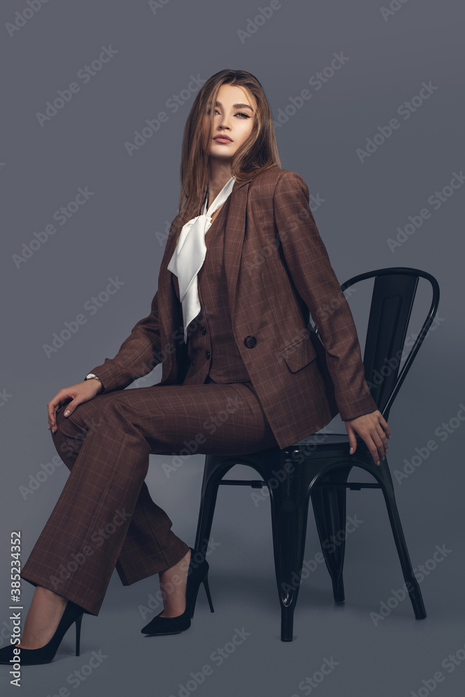 Fashion minimalist portrait of brunette female model on grey background. stylish clothing with scottish color, casual suit with women akcent  white silk shirt - obrazy, fototapety, plakaty 