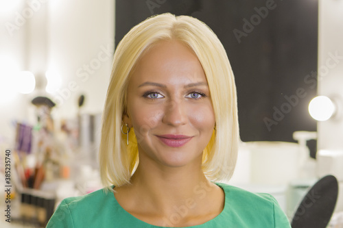 A young blonde 25-30 years old looks directly into the camera and smiles, close-up, selective focus.