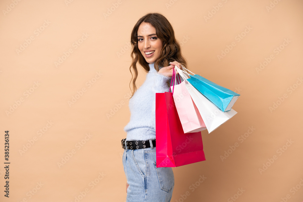 Young woman over isolated background holding shopping bags and smiling Young woman over isolated background holding shopping bags and smiling