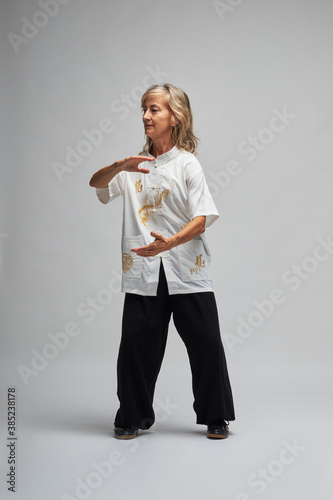 Foto Mature blonde woman practicing Chi kung and Tai Chi on a white background