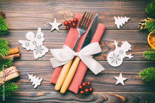 Top view of utensils on festive napkin on wooden background. Christmas decorations with dried fruits and cinnamon. Close up of New year dinner concept