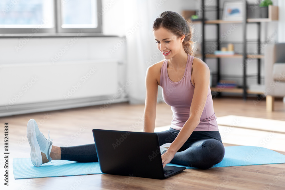 fitness, technology and healthy lifestyle concept - woman with laptop computer doing sports at home fitness, technology and healthy lifestyle concept - woman with laptop computer doing sports at home