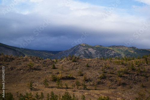 Baikal grassy mountains covered with green trees. Autumn landscape. Cloudy sky