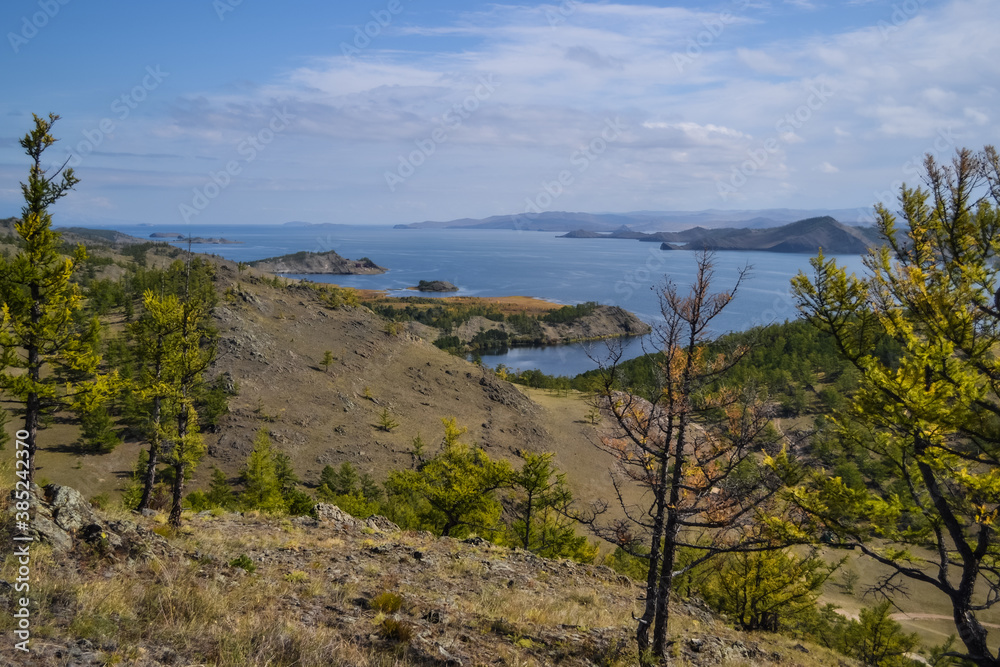 Autumn view of bay of Lake Baikal with islands and peninsulas and mountains on horizon. Blue water, yellow and green trees. Siberia landscape Autumn view of bay of Lake Baikal with islands and peninsulas and mountains on horizon. Blue water, yellow and green trees. Siberia landscape