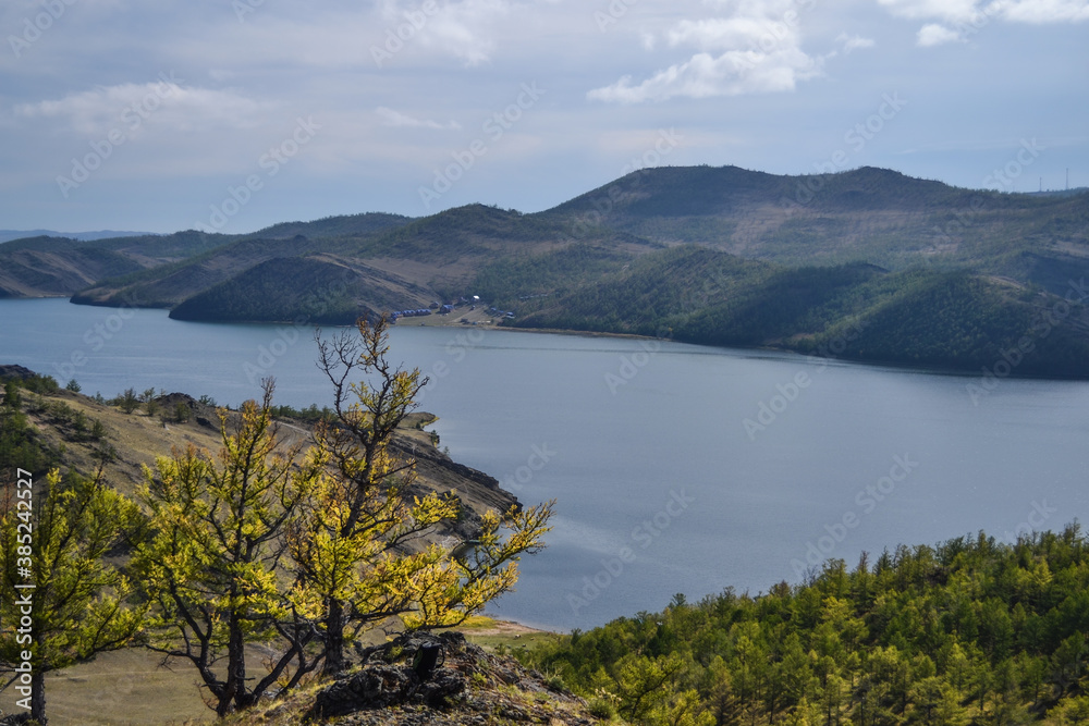 Autumn view of bay of Lake Baikal with peninsulas and mountains on horizon. Blue water, yellow and green trees