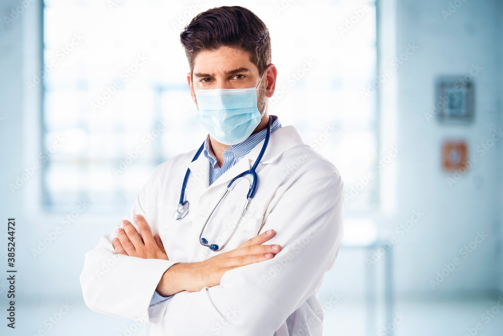 Portrait of male doctor wearing face mask while standing in the hospital foyer Portrait of male doctor wearing face mask while standing in the hospital foyer