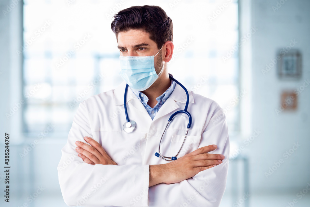 Portrait of male doctor wearing face mask while standing in the hospital foyer Portrait of male doctor wearing face mask while standing in the hospital foyer
