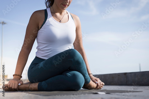 Sporty young woman doing Yoga exercises using a gym mat along the beach in Lisbon, Portugal. Playful woman working as freelance Yoga teacher doing fitness workout on the beach at sunset. Healthy life © Martina