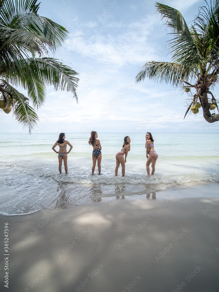 group of beautiful asian women in bikini posting on tropical sea beach with palm tree. Koh Kut, Thailand.