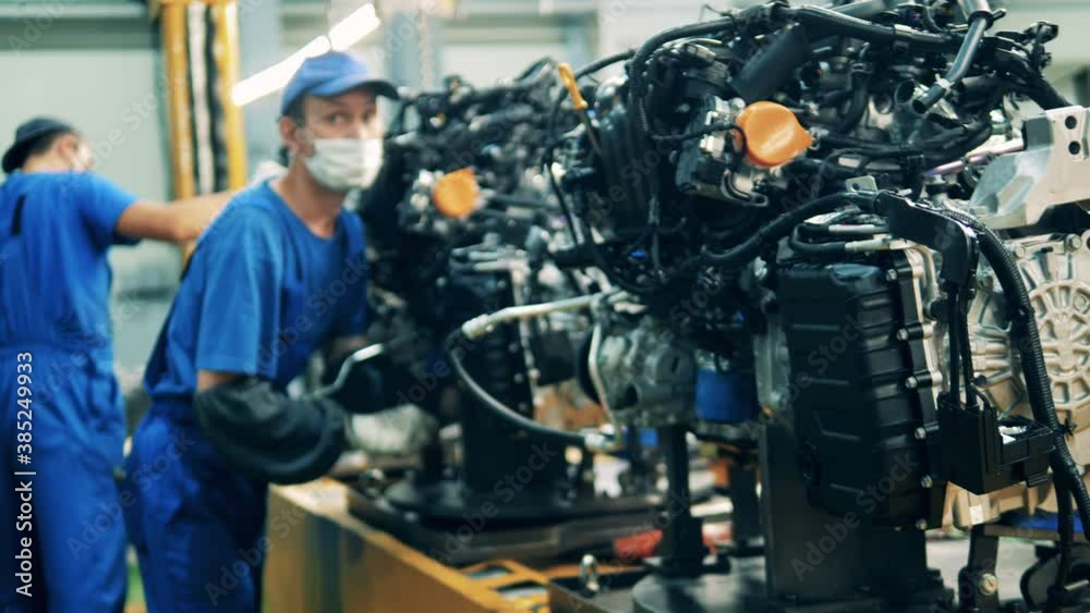 Car engines are getting assembled by factory workers. Automobile factory, car production, auto production line. Car engines are getting assembled by factory workers. Automobile factory, car production, auto production line.