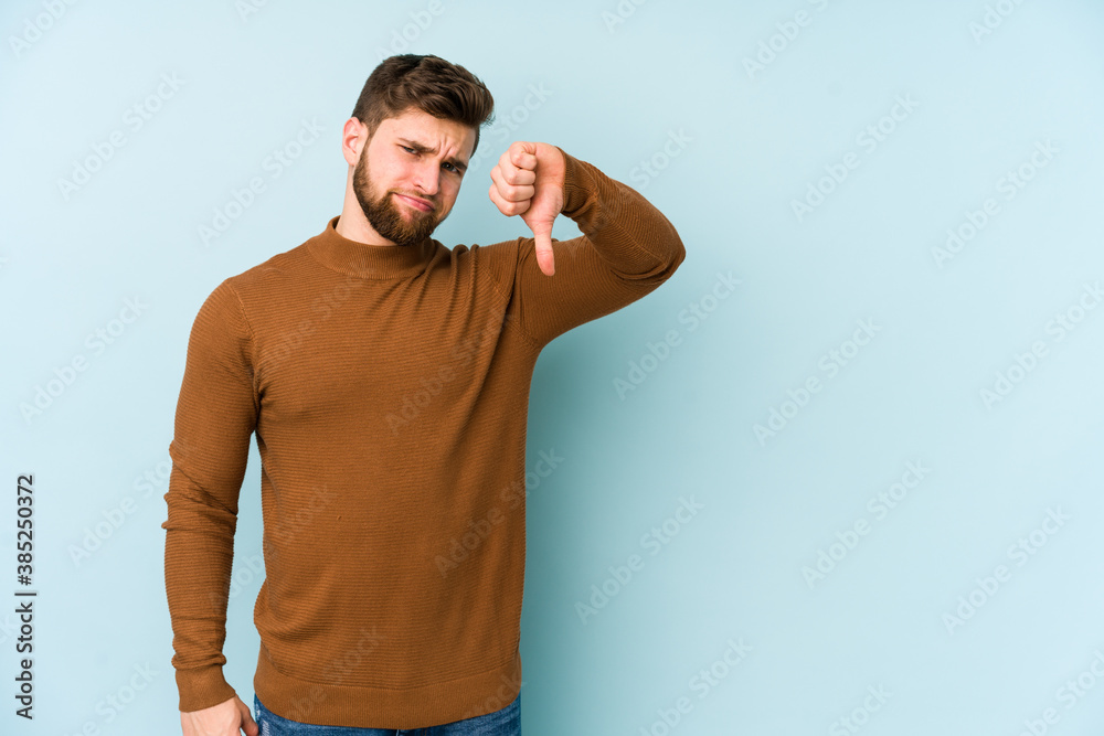 Young caucasian man isolated on blue background showing thumb down, disappointment concept. Young caucasian man isolated on blue background showing thumb down, disappointment concept.