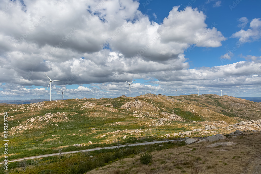 Mountains landscape and view of a wind turbines on top, cloudy sky as background Mountains landscape and view of a wind turbines on top, cloudy sky as background