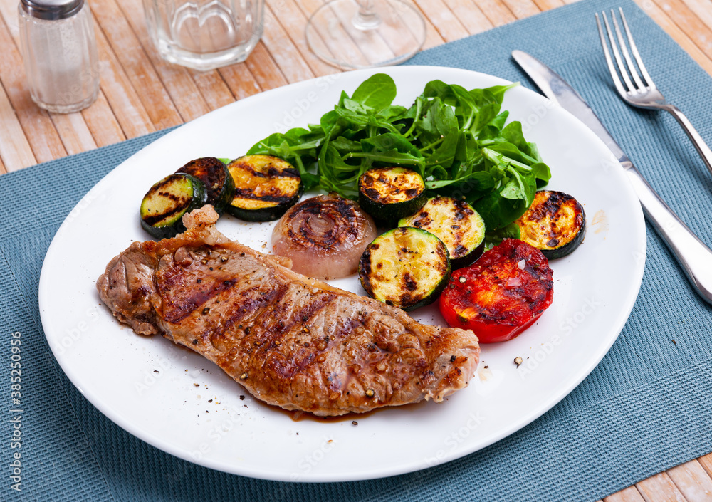 Beef steak served with grilled zucchini, onion, tomato and mash salad