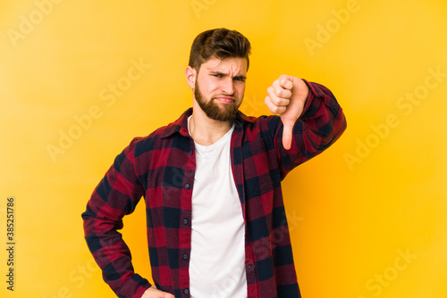 Fotografie, Tablou Young caucasian man isolated on yellow background showing thumb down, disappointment concept