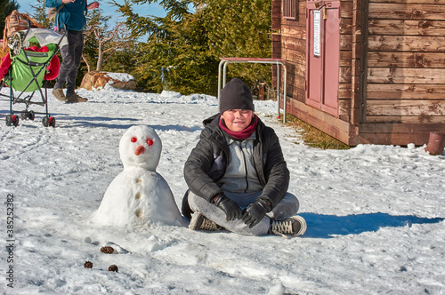 Family, boy, smiling, posing with snowman, playing and having fun in snow, ski resort, sierra nevada, granada, andalusia, spain