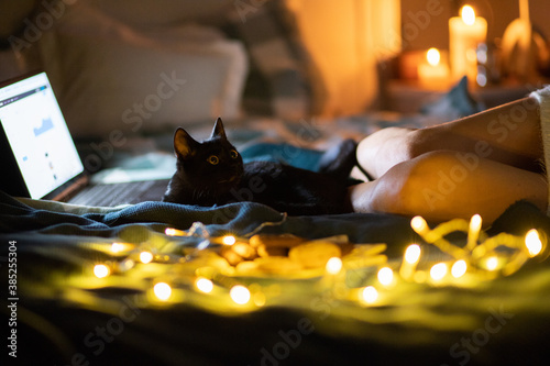 cozy Christmas at home woman in wool socks and black cat in bed