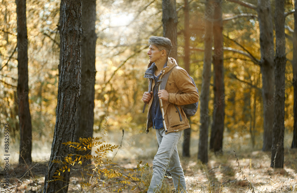 traveler casual style man walking in woods with backpack, single hiking in autumn forest. Concept hiking people in nature traveler casual style man walking in woods with backpack, single hiking in autumn forest. Concept hiking people in nature