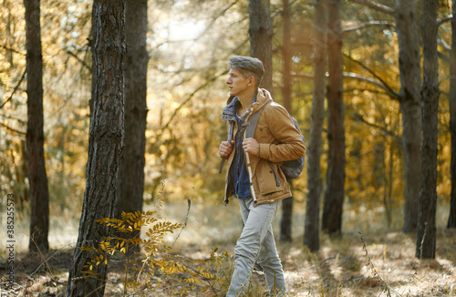traveler casual style man walking in woods with backpack, single hiking in autumn forest. Concept hiking people in nature