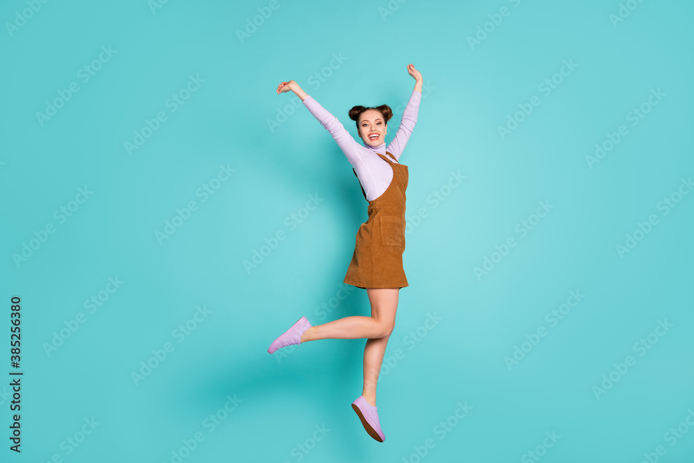 Full body photo of excited delightful lucky lady champion hooray jump raise hands breakthrough gesture wear two buns purple sneakers autumn trendy brown mini dress isolated teal color background