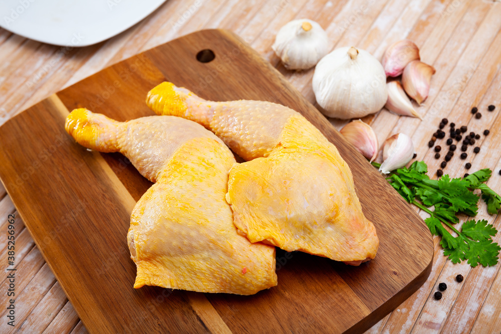 Fototapeta premium Raw chicken legs on cutting board and plate