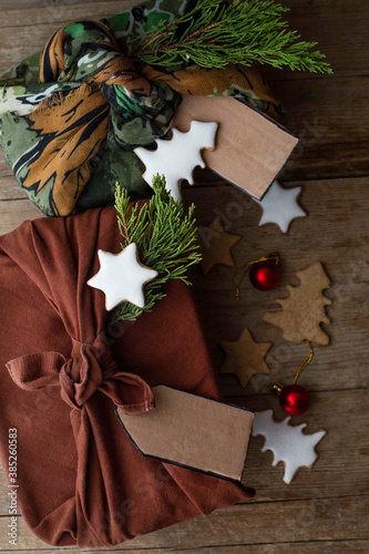 Christmas gifts packed furoshiki lie on a brown wooden table. zero waste concept