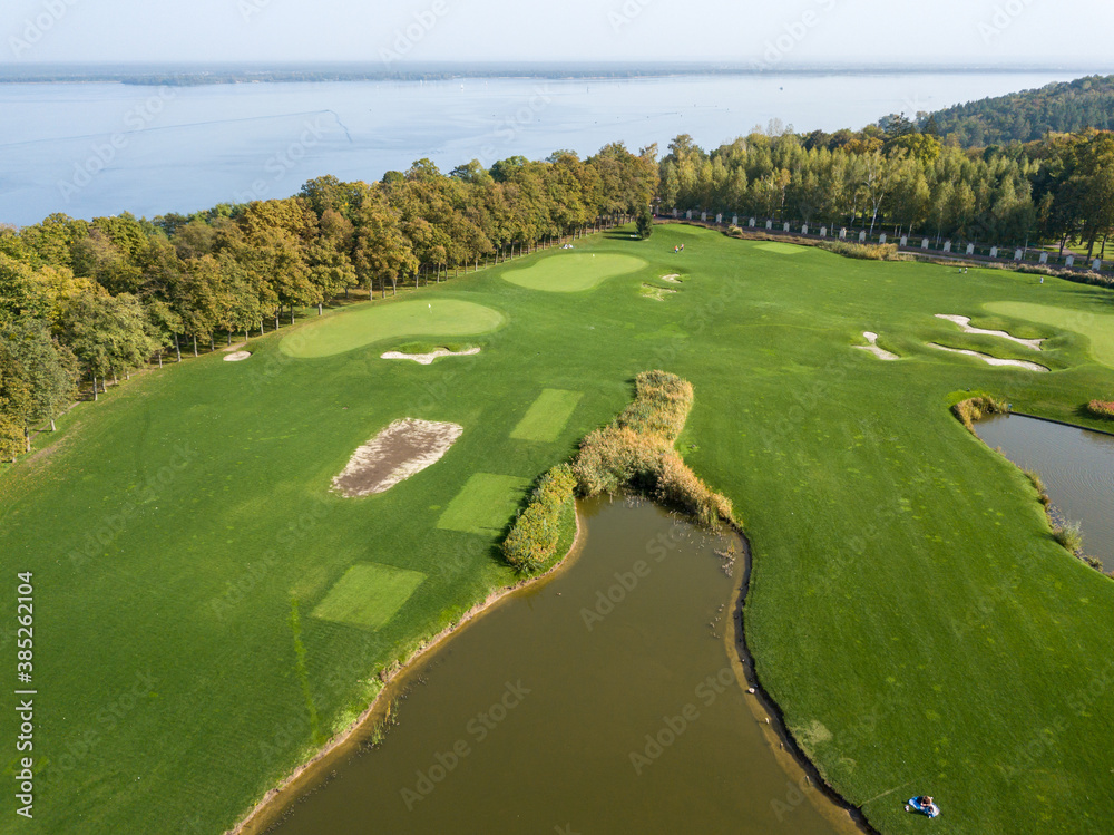 Aerial drone view. Lake with a fountain among a green golf course