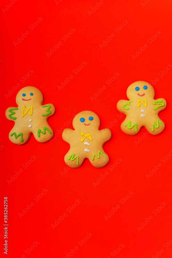Three gingerbread men are located on a red background. Flat lay. New Year and Christmas concept. There is a place for text