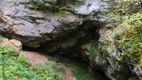 Slide over to reveal a cave entrance in rocky cliff photo