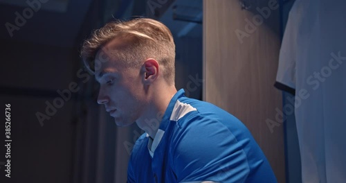 Football fan holding phone and betting in internet with the smart phone at empty fitting room, soccer player, man playing games on phone after match, professional game, online bets and casino