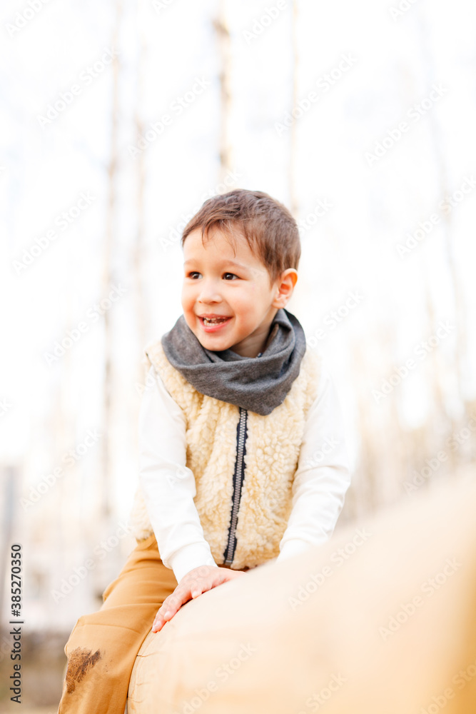 boy walks and laughs in the spring forest, beige and brown colors boy walks and laughs in the spring forest, beige and brown colors
