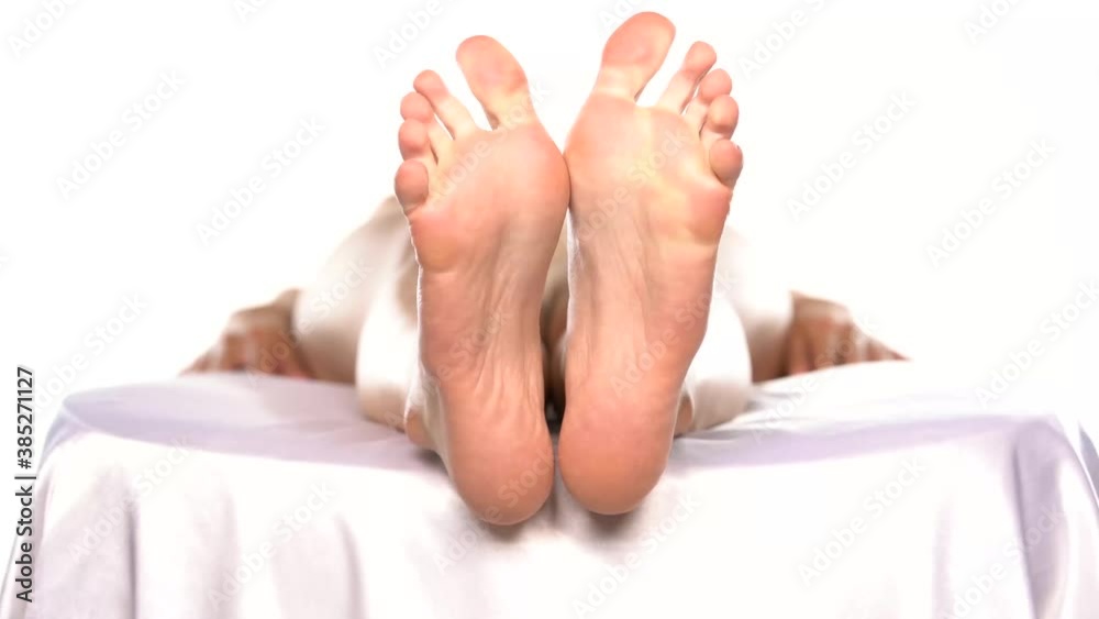 bare feet of a woman lying on a bed and relaxing on a white background bare feet of a woman lying on a bed and relaxing on a white background