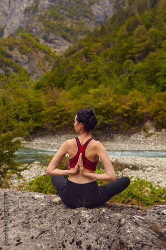 Yoga classes in nature. The concept of playing sports alone. Social exclusion. A woman does yoga on rocks, near a mountain river flows © Мария Чичина