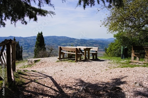 An empty wooden picnic table with wooden benches in a park with a panoramic view (Gubbio, Umbria, Italy, Europe)