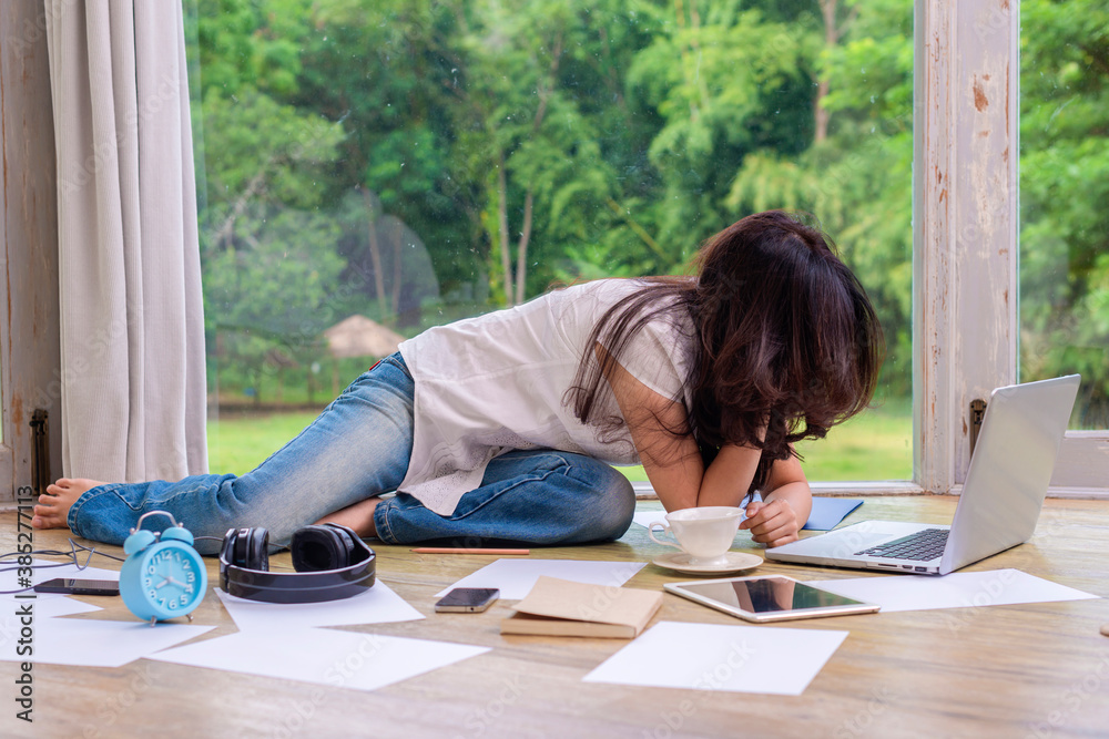Stressed asian woman with frustrated, overworked at home and near the girl is alarm clock, pencil, book, tablet, headphones and background blur beautiful garden at home. Stressed asian woman with frustrated, overworked at home and near the girl is alarm clock, pencil, book, tablet, headphones and background blur beautiful garden at home.